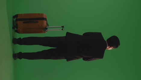 full body of back view asian businessman traveler with luggage crossing arms and looking around while standing in the green screen background studio, during sunset time