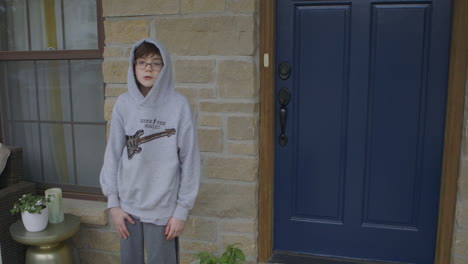 little boy with a hoodie standing on the porch in quarantine