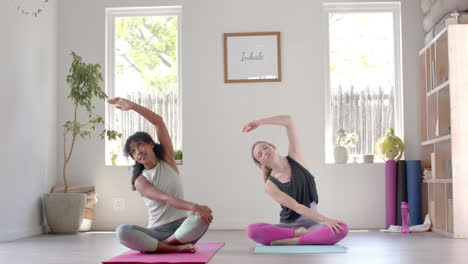 happy diverse fitness women exercising and stretching on mat in white room, slow motion