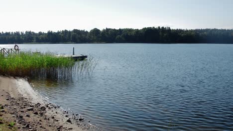 stone pier, lake with boat. green forest, cloudy