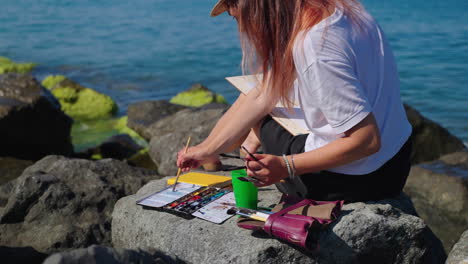 woman painting seascape on the beach