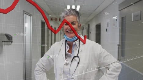 senior woman doctor wearing stethoscope standing hospital corridor, showing financial chart grid