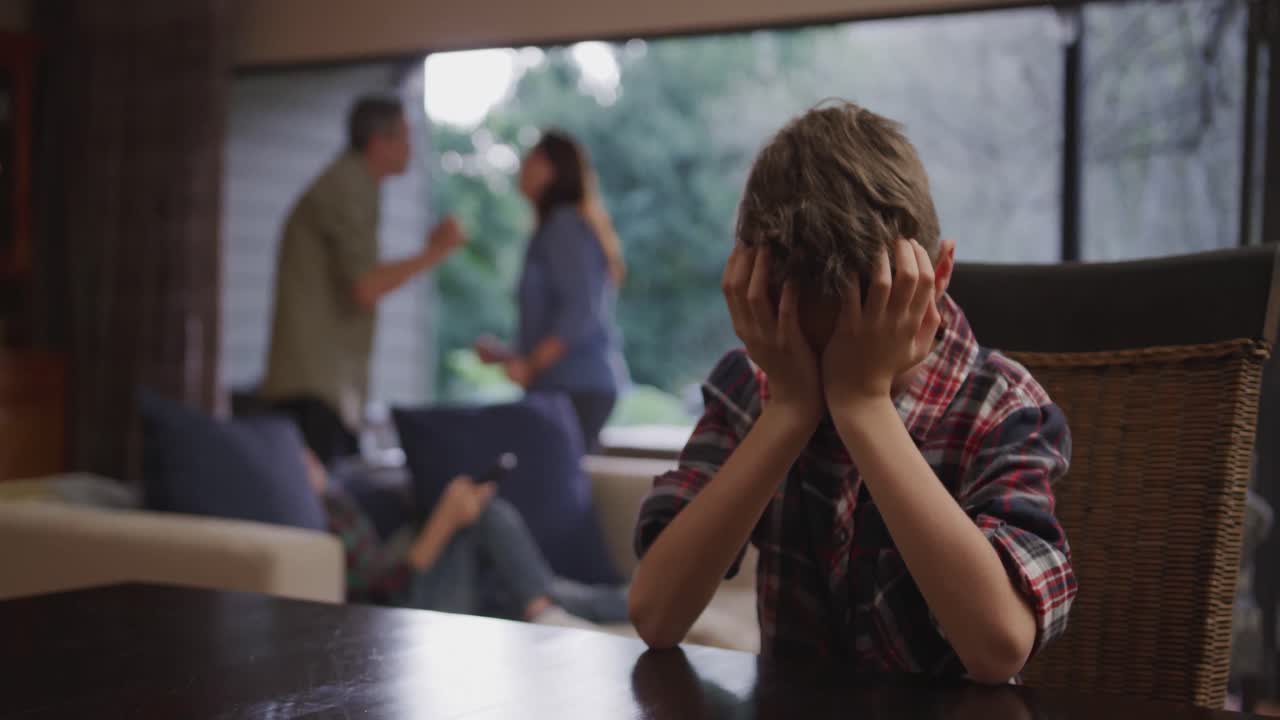 머리를 손에 들고 테이블에 앉아 있는 백인 소년