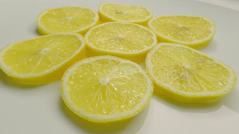 lemon, citrus fruit, cut into pieces, rotates on white plate.