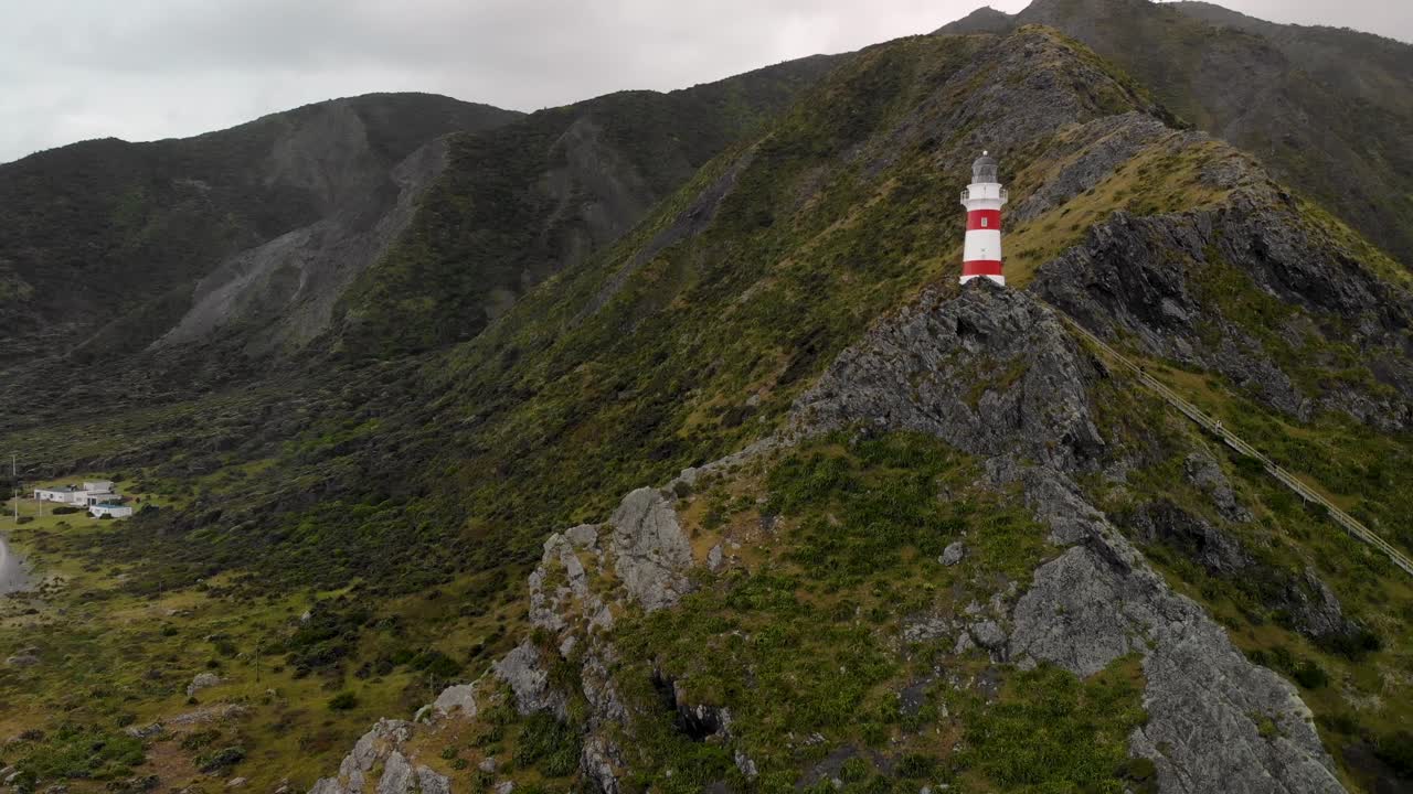 faro de cape palliser en la cima de un acantilado de una montaña rocosa en cape palliser, nueva zelanda