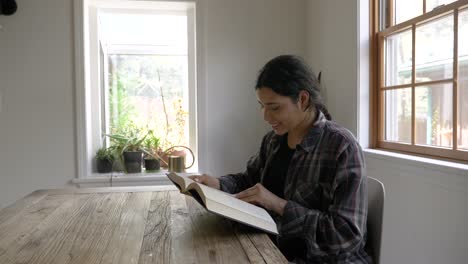 smiling puerto rican female teenager sitting reading positive emotion book novel in modern home interior