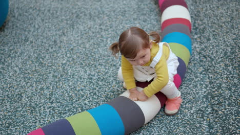 Feliz-Niña-Pequeña-De-3-Años-Sentada-En-Una-Almohada-Larga-Y-Colorida-En-El-área-De-Juegos-Dentro-De-Un-Centro-Comercial