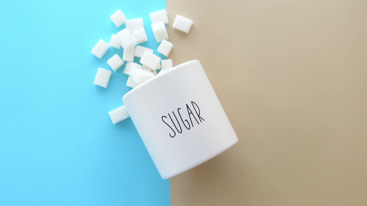 cubos de azúcar blanco en un tazón sobre un fondo azul y marrón