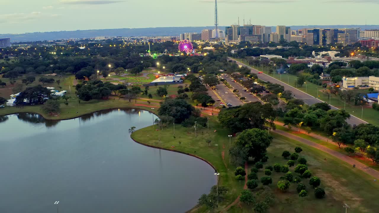 vista aérea del parque de la ciudad en brasilia con la rueda de la ferris y el lago al anochecer