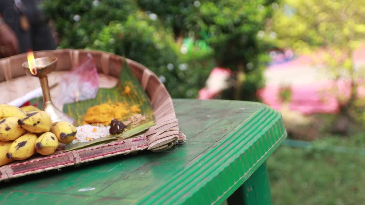 Primo piano degli oggetti rituali per la cerimonia Haldi conservati in un cestino da cucina sulla sedia di plastica per la cerimonia nuziale