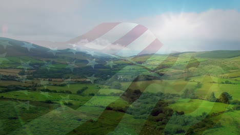 Digital-composition-of-waving-us-flag-against-aerial-view-of-the-grasslands