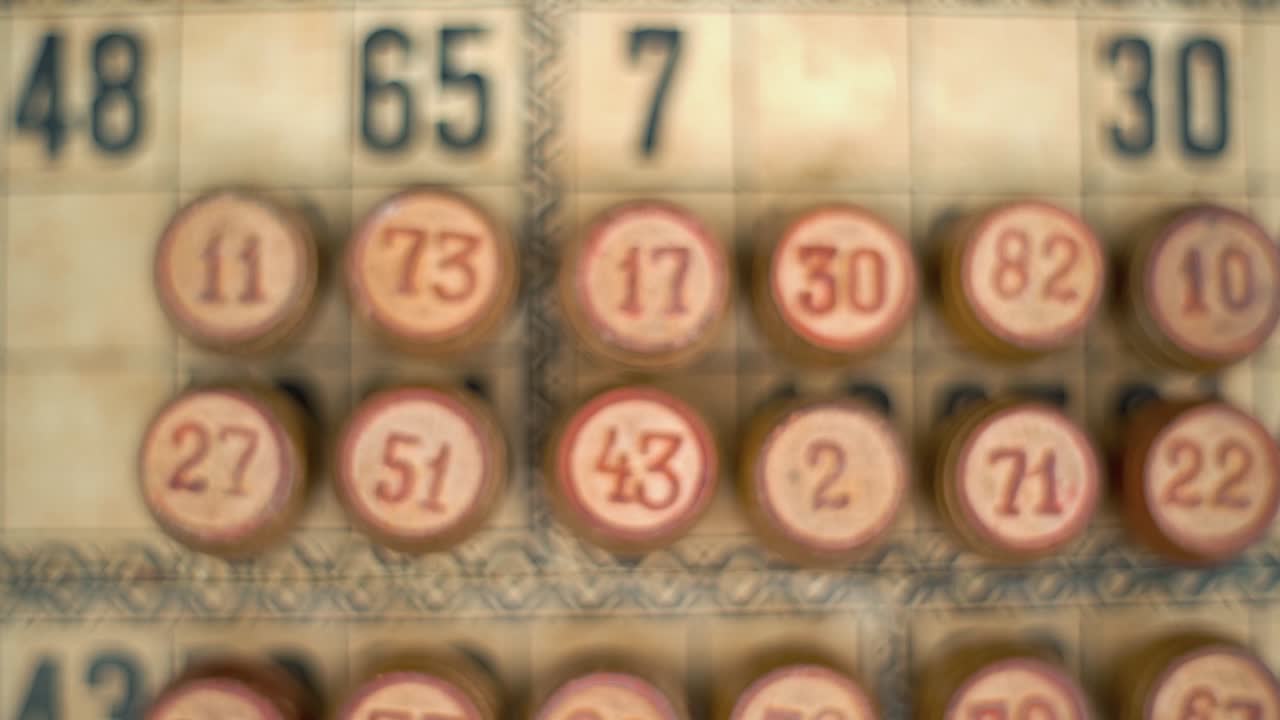 cinematográfico primer plano zoom suave en el disparo de un bingo barriles de madera, figuras de madera, en un antiguo fondo de números texturados, juego de mesa vintage, número de la suerte, iluminación profesional, cámara lenta 120 fps