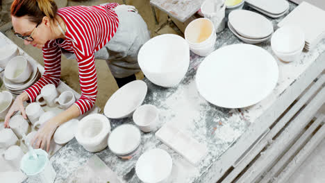 Female-potter-arranging-mugs-on-worktop-4k