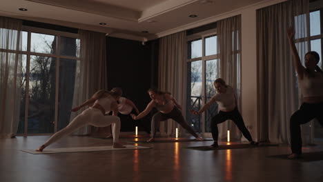 a group of women is engaged in stretching and balance with an instructor in a beautiful hall with large windows. healthy lifestyle group classes