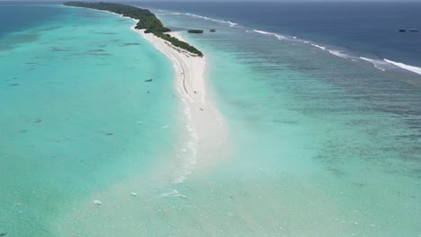 couple of people relaxing in crystal clear lagoon surrounding long beach sandbar in dhigurah island, maldives