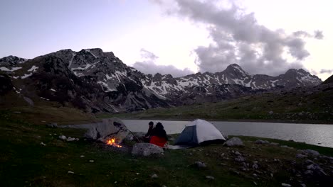 couple of travelers at dusk near a campfire