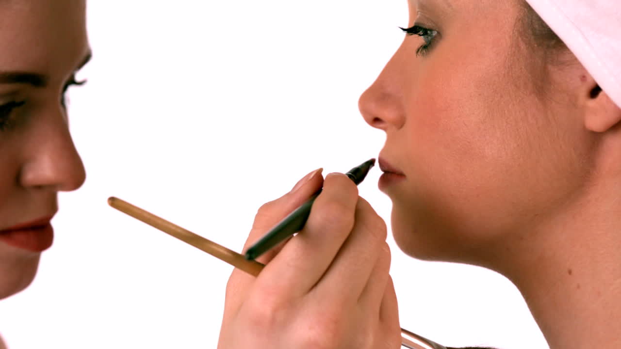 artista de maquillaje poniendo lápiz labial en la cara de las modelos