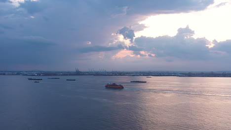 slow aerial pan shows two staten island ferries approaching each other in the new york harbor during a dramatic sunset