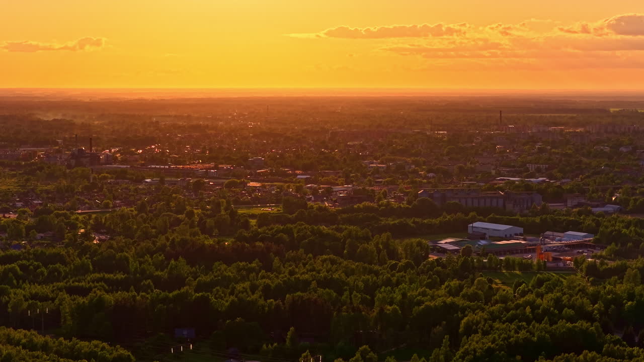 Cityscape during golden sunset with glowing sky and houses between trees