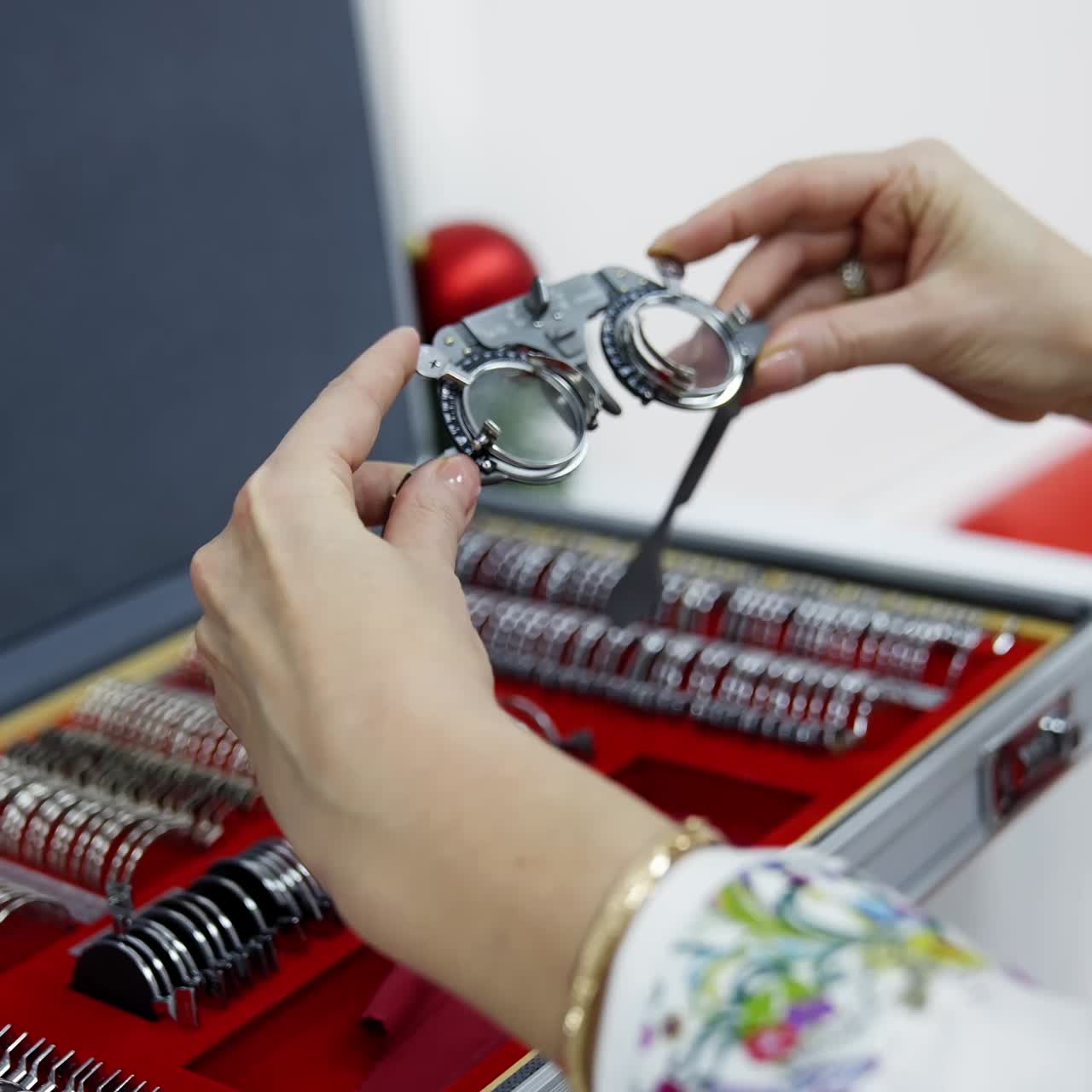 Testing glasses in the hands of ophthalmologist. Doctor selecting necessary lenses for trial frame on the background of case with many lenses