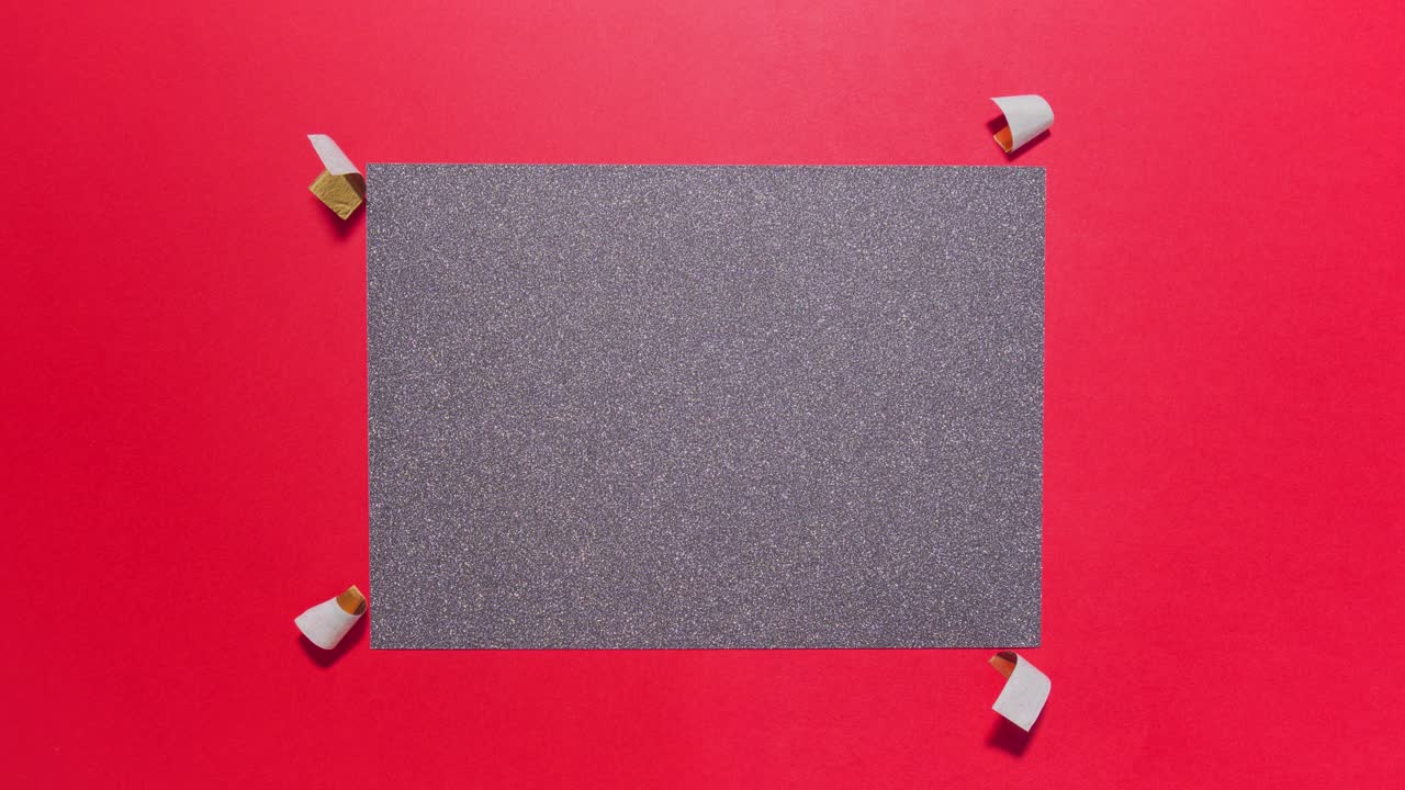 Stop motion dark glitter card appears and is taped on bright red background with center copy space