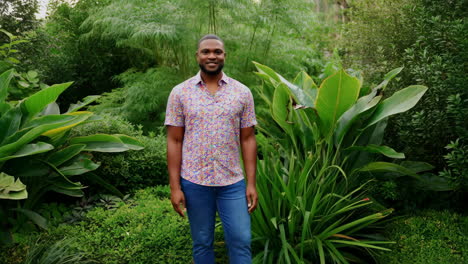 a smiling man standing in a lush green garden