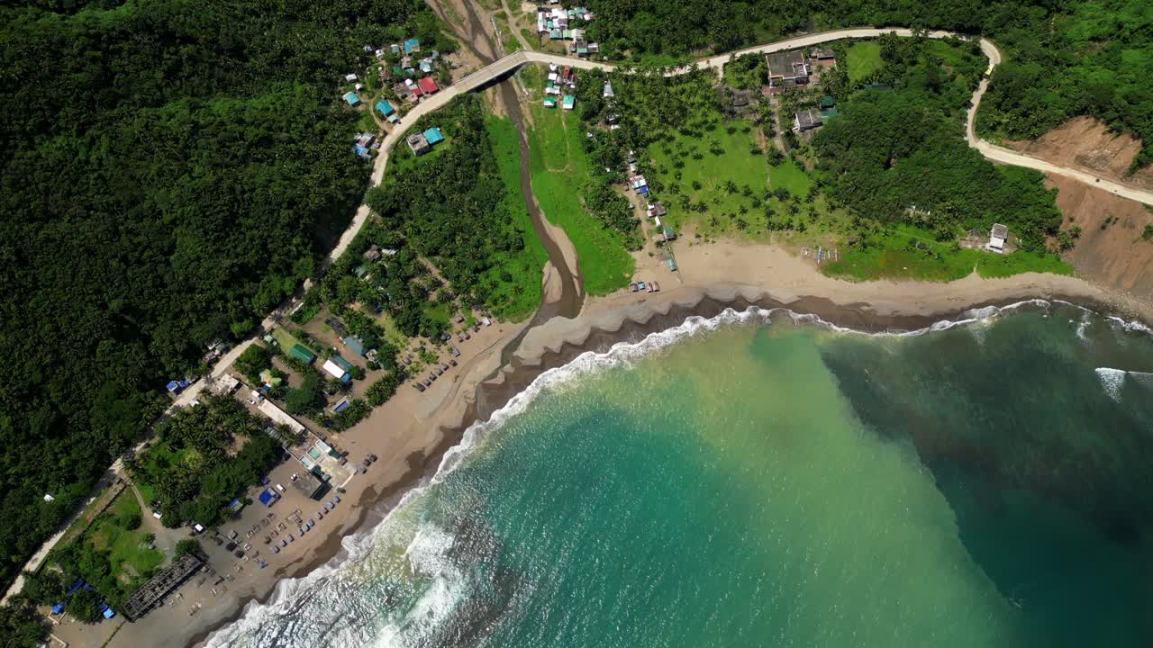 Diagonal pan aerial top view near the Matawe Rock Formations in Dingalan, Aurora, sweeping across turquoise waters, sandy shoreline, and lush green hills along the coast