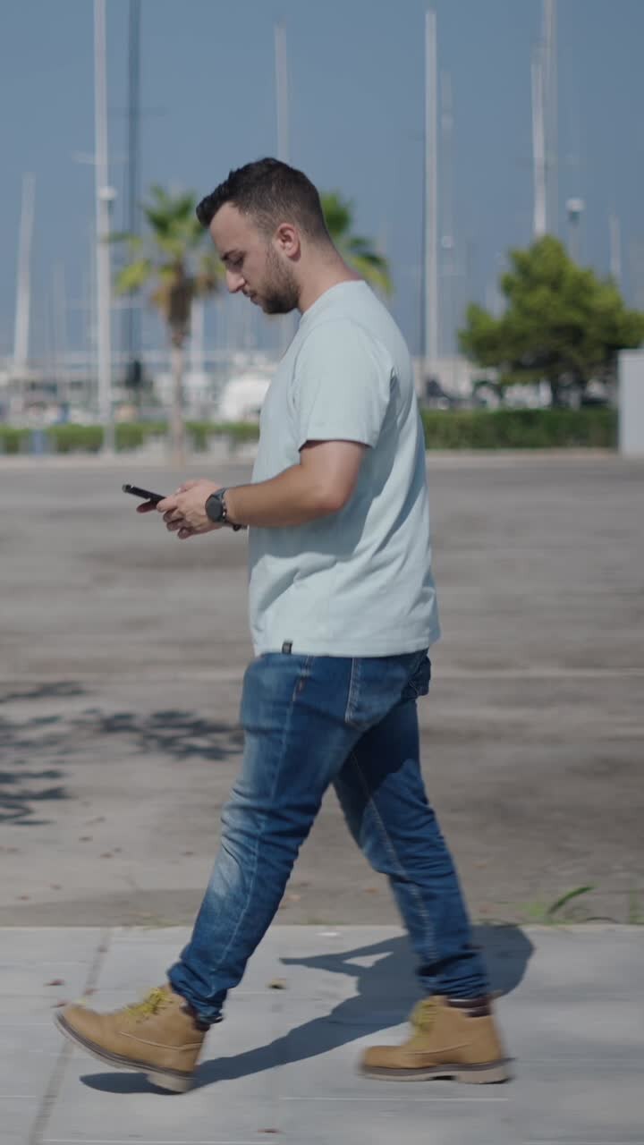 Man walking and using smartphone near marina