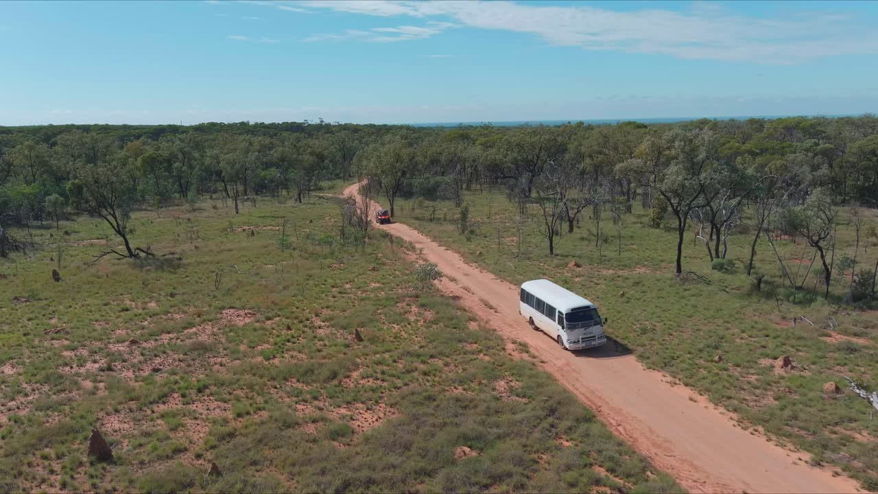 un autobús conduciendo a lo largo de un camino de tierra en el interior de australia