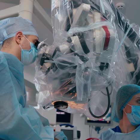 modern surgery through the microscope. professional doctor and woman assistant doing a neurosurgery using advanced medical equipment.