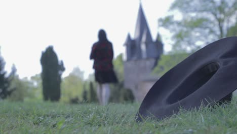 a hat in the gras and a girl walking away in the background