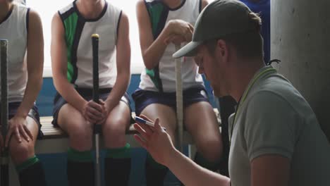 hockey coach talking with female players in locker room