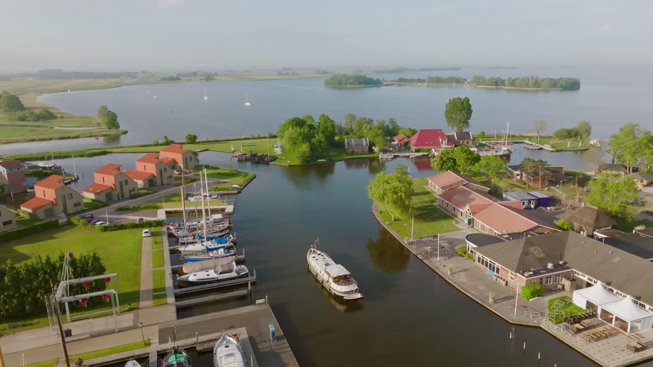 Aerial zoom in on Luxemotor boat entering the marina in Heeg, Netherlands, surrounded by yachts, docks and traditional houses