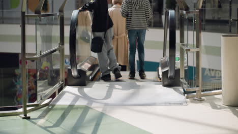 a bustling mall scene with people moving about and some going down the escalator. this video highlights the dynamic environment and activity within the mall