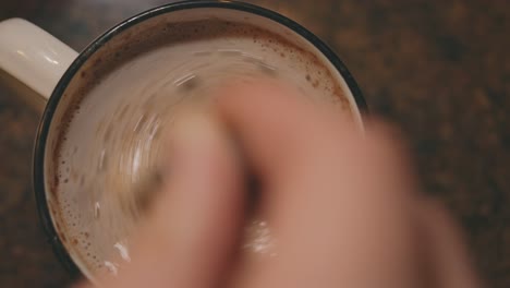 hand mixing a mug of hot chocolate drink using spoon - static, high angle shot