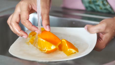 woman washing oranges in the kitchen sink