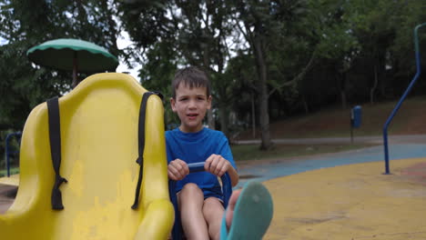 Boy-going-up-and-down-on-teeter-totter-outside-on-summer-day