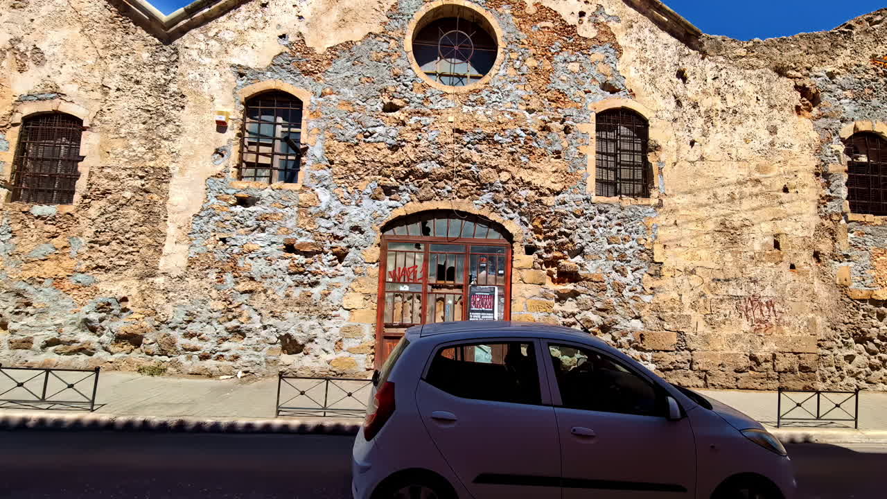 Weathered stone building with arched door and windows, showing historic architecture in Chania, Greece