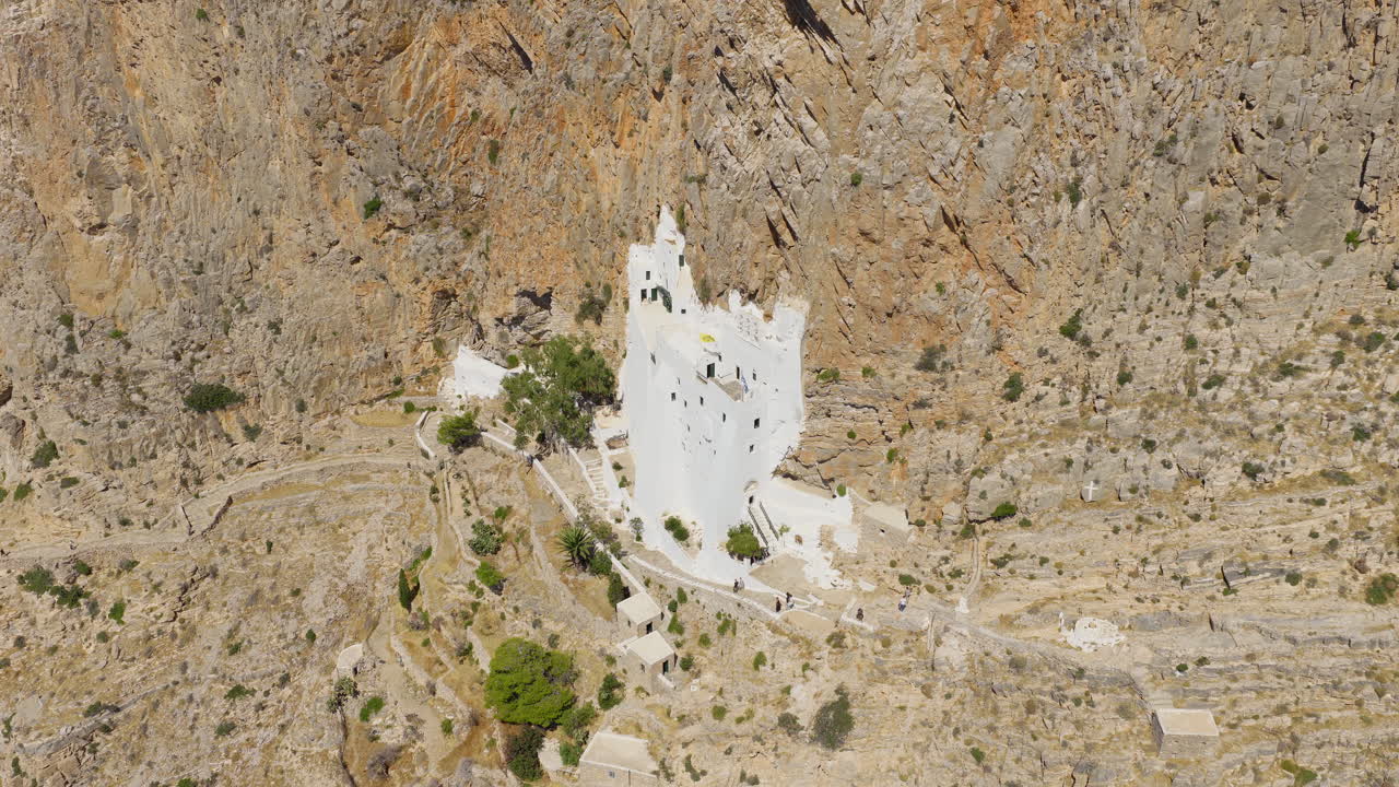 Slow panning drone shot of the legendary Chozoviotissa Monastery on Amorgos, highlighting its stunning architecture and dramatic location