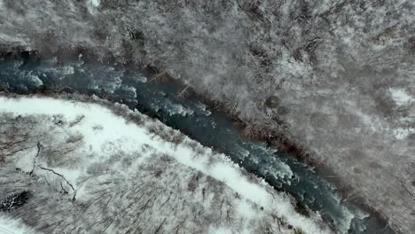 hermoso río de invierno que fluye por la ladera nevada, bajando la antena giratoria