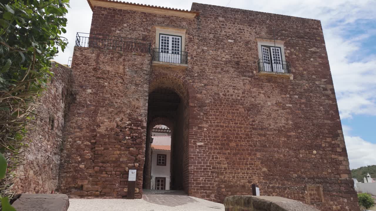 A historic stone building with arched gates and windows in Silves, Portugal, under a partly cloudy sky