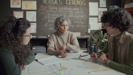 mature female teacher and two students discussing topics in english class