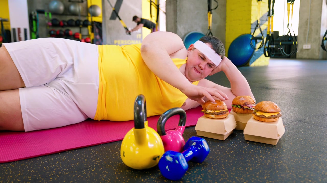 Uomo in sovrappeso che fatica ad allenarsi, tentato dagli hamburger in palestra