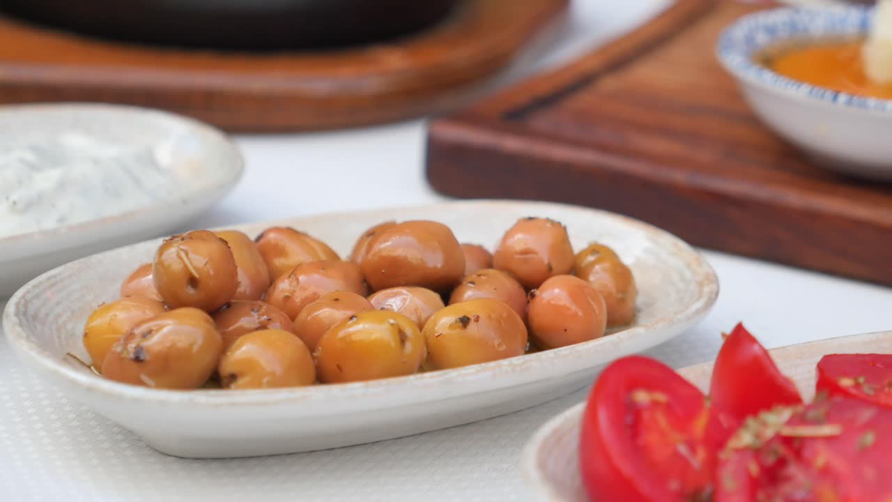 Close up of a dish of olives with various accompaniments