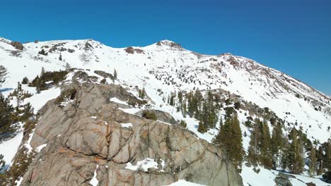 Aerial-flyover-large-rock-cliff-toware-mountains,-Carson-Pass,-California