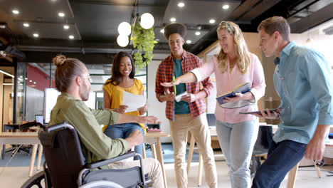 Diverse-male,-female-and-disabled-colleagues-stacking-hands-at-casual-office-meeting,-slow-motion