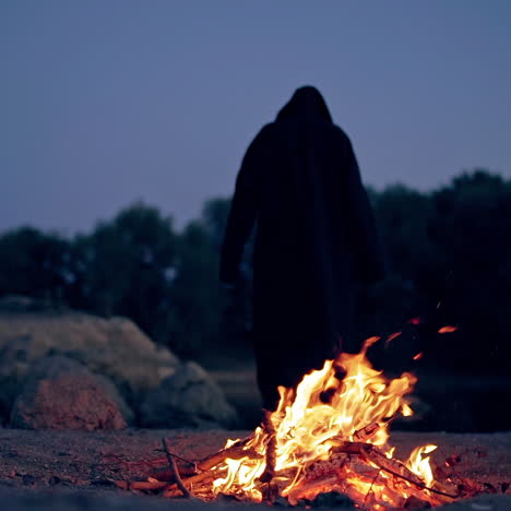 wicked witch holds ritual by the fire. halloween costume.