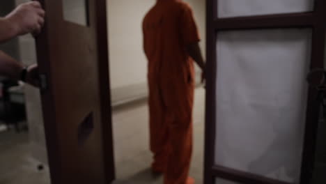 prison guards escort a prisoner into his cell and shut prison door locking him inside