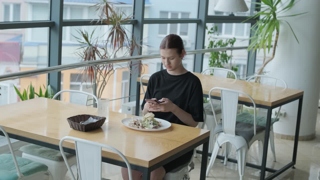 una chica comiendo ensalada en un café.