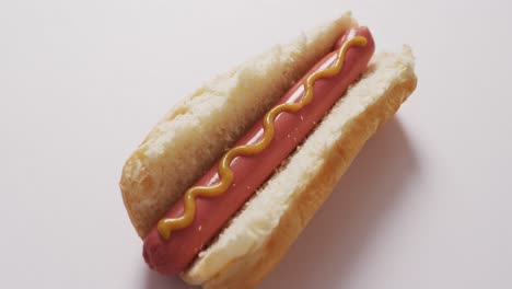 video of hot dog with mustard on a white surface